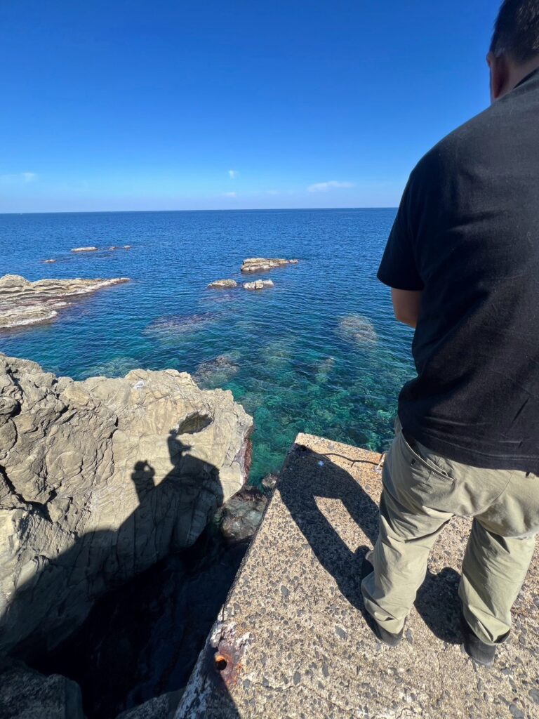 小伊津の海に向かって釣りをする人の後ろ姿